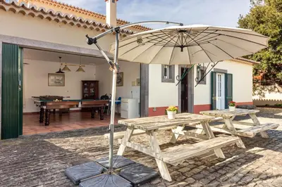 a picnic table with an umbrella in front of a house at Villa Retiro in Canhas