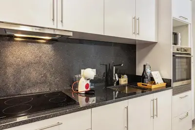 a kitchen with white cabinets and a black counter top at Casa do Porto in Paul do Mar