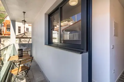 a room with a window and a balcony with a table at Casa do Porto in Paul do Mar