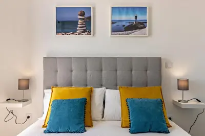 a bedroom with a bed with blue and yellow pillows at Casa Homem do Mar in Paul do Mar