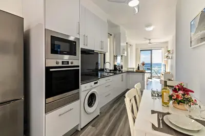 a kitchen with white cabinets and a table with a dining room at Casa Homem do Mar in Paul do Mar