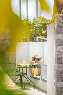 a woman in a hat sitting at a table at Casa da Lombada by An Island Apart in Funchal