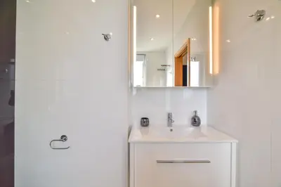 a white bathroom with a sink and a mirror at POLA SeaView Apartment by MOJE Holiday in Lagos