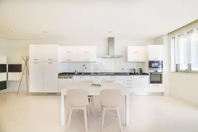 a white kitchen with a white table and chairs at POLA SeaView Apartment by MOJE Holiday in Lagos