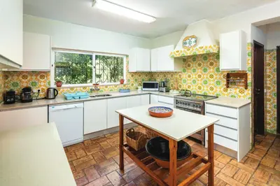 a kitchen with white cabinets and a table in it at Quinta Kilara in Luz