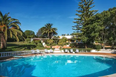 a large swimming pool with chairs and palm trees at Quinta Kilara in Luz