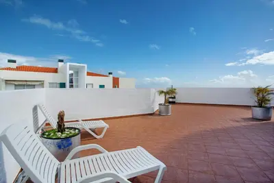 a balcony with two white chairs and a potted plant at Apartamento Lolita com Terraço in Caniço