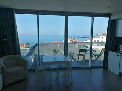 a living room with a table and a view of the ocean at Apartments Madeira Barreirinha in Funchal