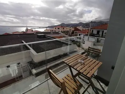 a balcony with a wooden table and chairs on a building at Apartments Madeira Barreirinha in Funchal