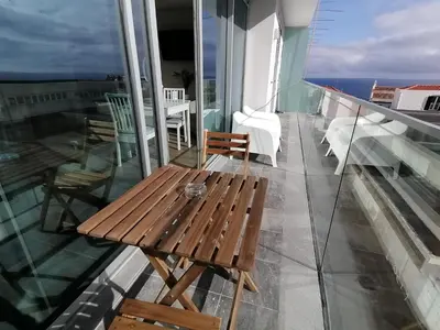 a wooden table on a balcony with a view of the ocean at Apartments Madeira Barreirinha in Funchal