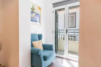 a living room with a blue chair and a table at Cosy Central by Atlantic Holiday in Funchal