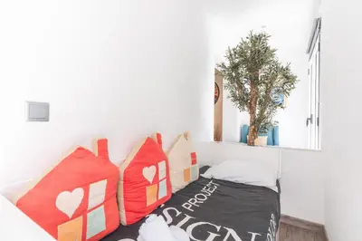 a small bed in a white room with red pillows at Cosy Central by Atlantic Holiday in Funchal