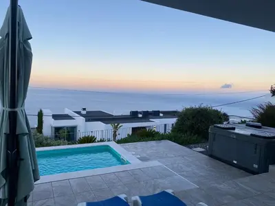 a villa with a swimming pool and an umbrella at Villa Sundowner in Prazeres