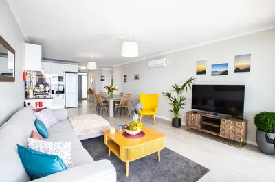 a living room with a white couch and a tv at Villa Sundowner in Prazeres