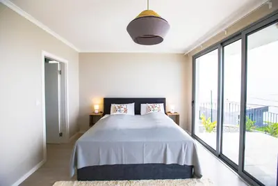 a bedroom with a large bed and large windows at Villa Sundowner in Prazeres