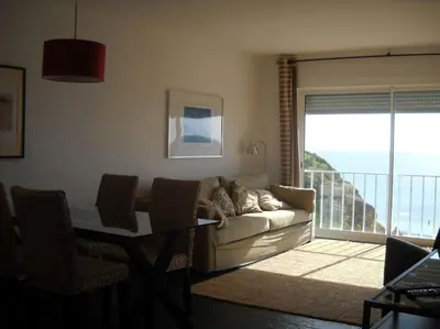 a living room with a couch and a table and a balcony at apartment with amazing sea view in Burgau