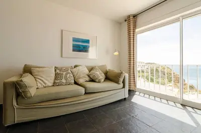 a couch in a living room with a large window at apartment with amazing sea view in Burgau