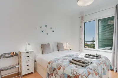a white bedroom with a bed and a window at Alta do Garajau II in Caniço