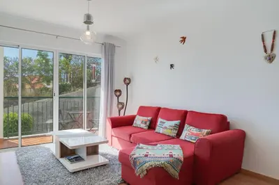 a red couch in a living room with a window at Alta do Garajau II in Caniço