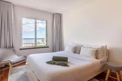 a bedroom with a large white bed and a window at Madeira Sea View Apartment in Caniço