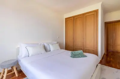 a white bed in a room with a wooden door at Madeira Sea View Apartment in Caniço