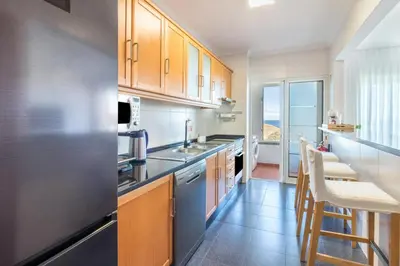 a kitchen with a stainless steel refrigerator and wooden cabinets at Madeira Sea View Apartment in Caniço