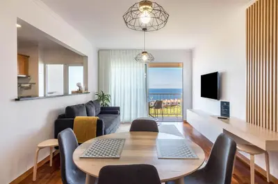 a living room with a dining room table and a couch at Madeira Sea View Apartment in Caniço