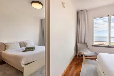 a bedroom with a bed and a window and a mirror at Madeira Sea View Apartment in Caniço
