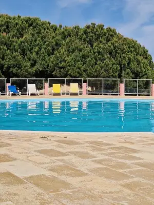 a blue swimming pool with chairs and trees at Lighthouse Apartment in Luz
