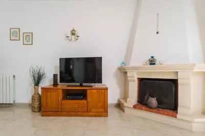 a living room with a tv and a fireplace at cozy sunny peaceful flat with swimming pool in Burgau