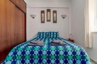 a bedroom with a bed with blue and green at cozy sunny peaceful flat with swimming pool in Burgau