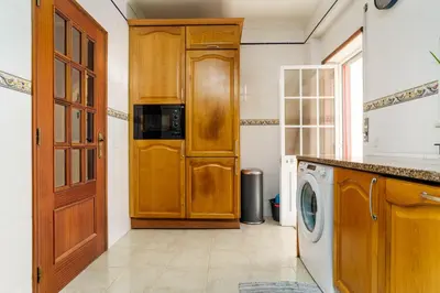 a kitchen with a washing machine and a wooden door at cozy sunny peaceful flat with swimming pool in Burgau