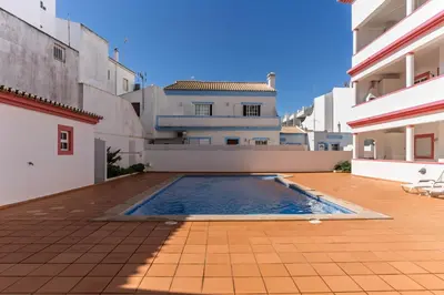 a swimming pool in the courtyard of a building at cozy sunny peaceful flat with swimming pool in Burgau