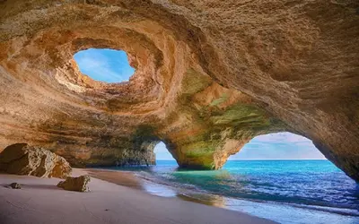 a large rock formation on a beach with the ocean at Villa Alcione in Sagres