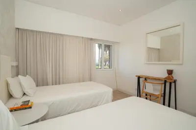 a hotel room with two beds and a table and a mirror at Dune Beach CoLiving in Porto Santo