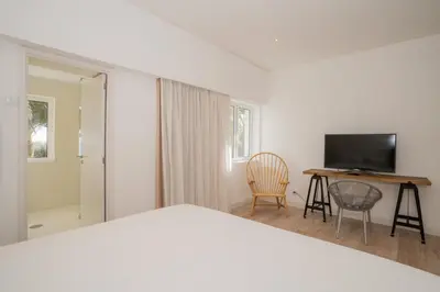 a bedroom with a bed and a desk and a television at Dune Beach CoLiving in Porto Santo
