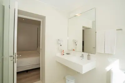 a white bathroom with a sink and a mirror at Dune Beach CoLiving in Porto Santo