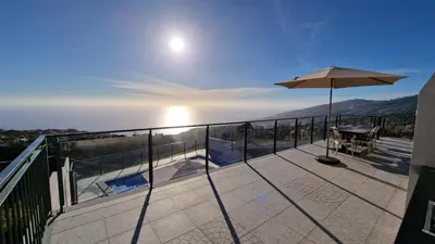 a balcony with a table and an umbrella at Casa Bella Vista - Calheta in Arco da Calheta