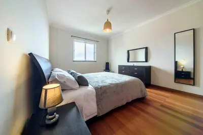 a bedroom with a bed and a table with a lamp at Garajau Ocean View in Caniço