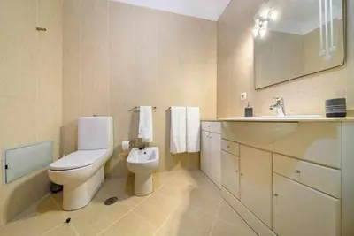 a white bathroom with a toilet and a sink at Garajau Ocean View in Caniço