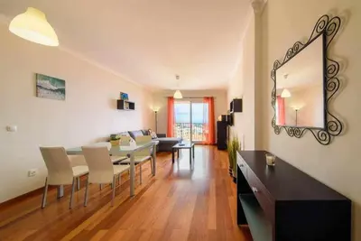 a dining room and living room with a table and chairs at Garajau Ocean View in Caniço