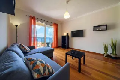 a living room with a blue couch and a table at Garajau Ocean View in Caniço