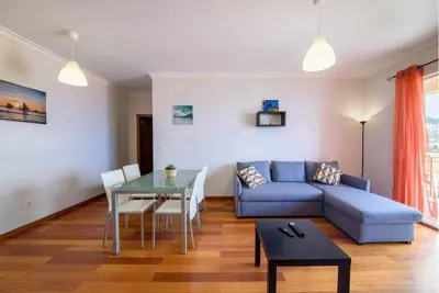 a living room with a blue couch and a table at Garajau Ocean View in Caniço