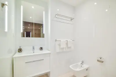 a white bathroom with a sink and a mirror at WIOLA SeaView Apartment by MOJE Holiday in Lagos