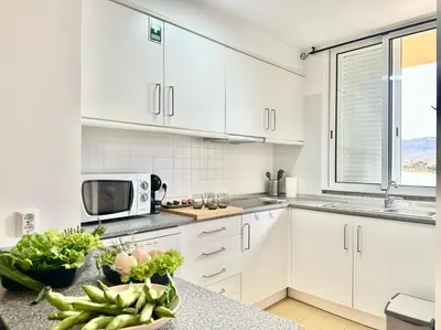 a kitchen with white cabinets and a microwave at Maria da Vinha Porto Santo Beach House in Porto Santo