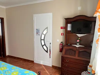 a bedroom with a bed and a tv and a door at Slice of ponta do sol Room 1 in Ponta do Sol