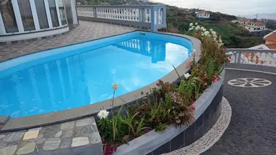 a large blue swimming pool on top of a house at Slice of ponta do sol Room 1 in Ponta do Sol
