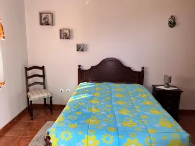 a bedroom with a bed with a blue and yellow blanket at Slice of ponta do sol Room 1 in Ponta do Sol