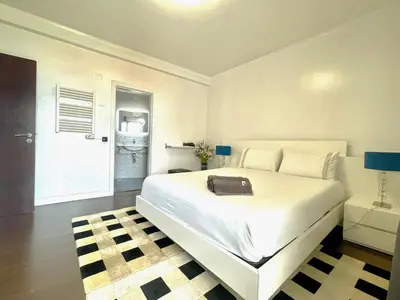 a white bedroom with a bed with a black briefcase on it at Villa Madeira island in Caniço