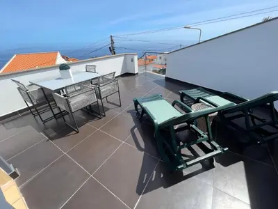 a balcony with a table and chairs on a roof at Villa Madeira island in Caniço